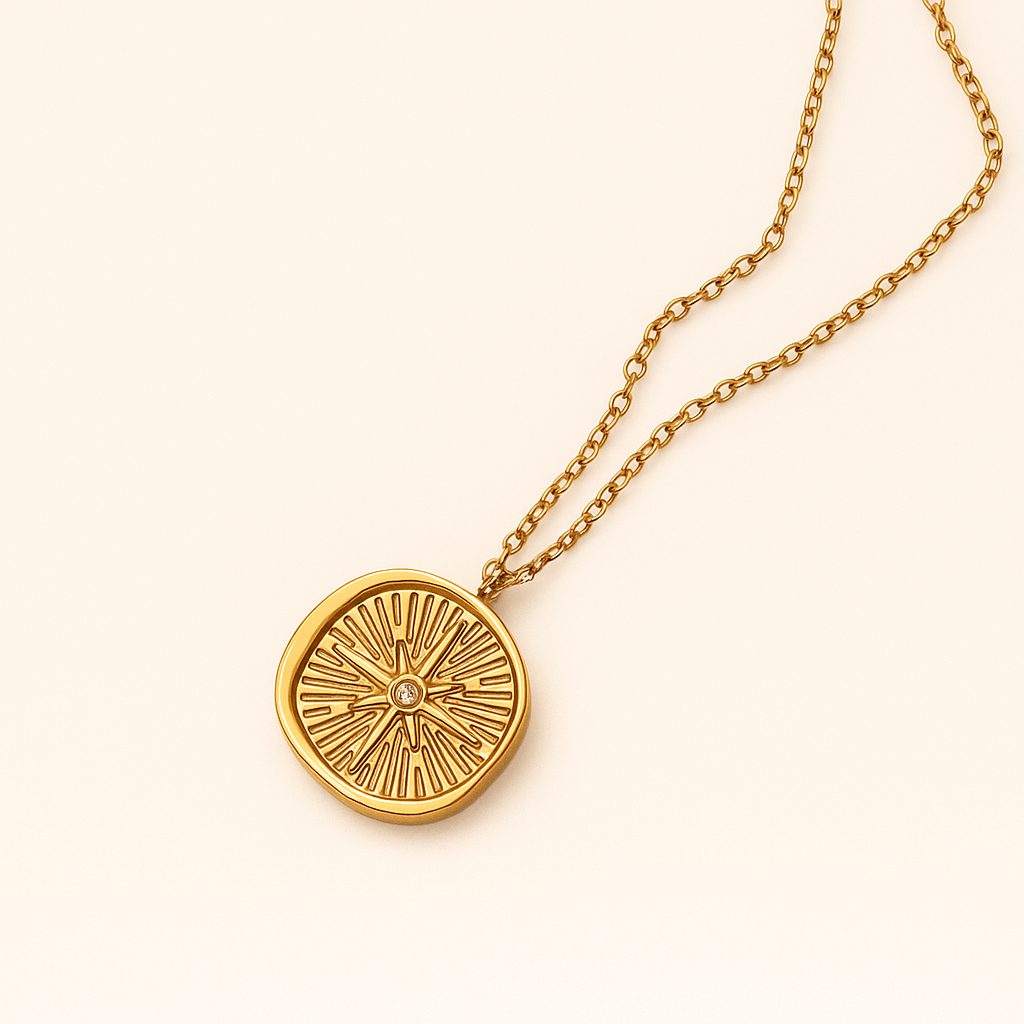 18k gold compass pendant necklace with engraved rays and a crystal center