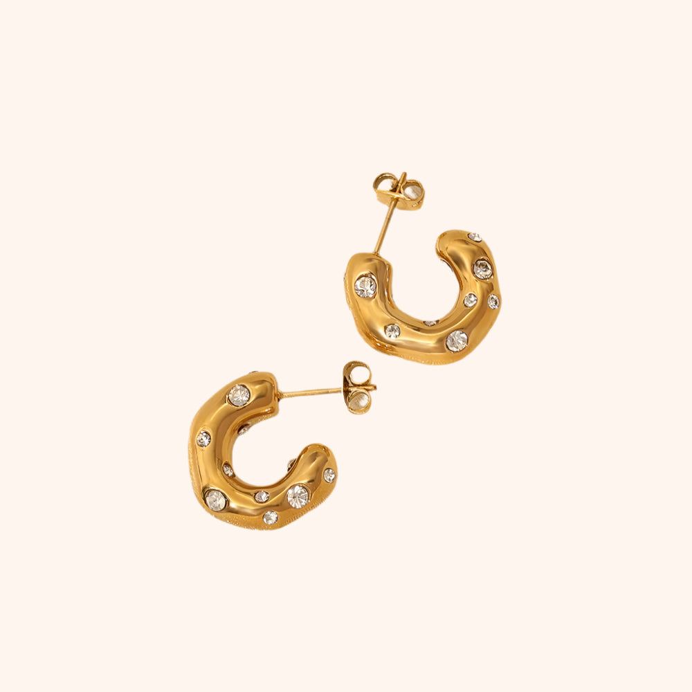 Pair of crystal-embellished chunky gold hoop earrings, highlighting their luxurious texture and glamorous style.