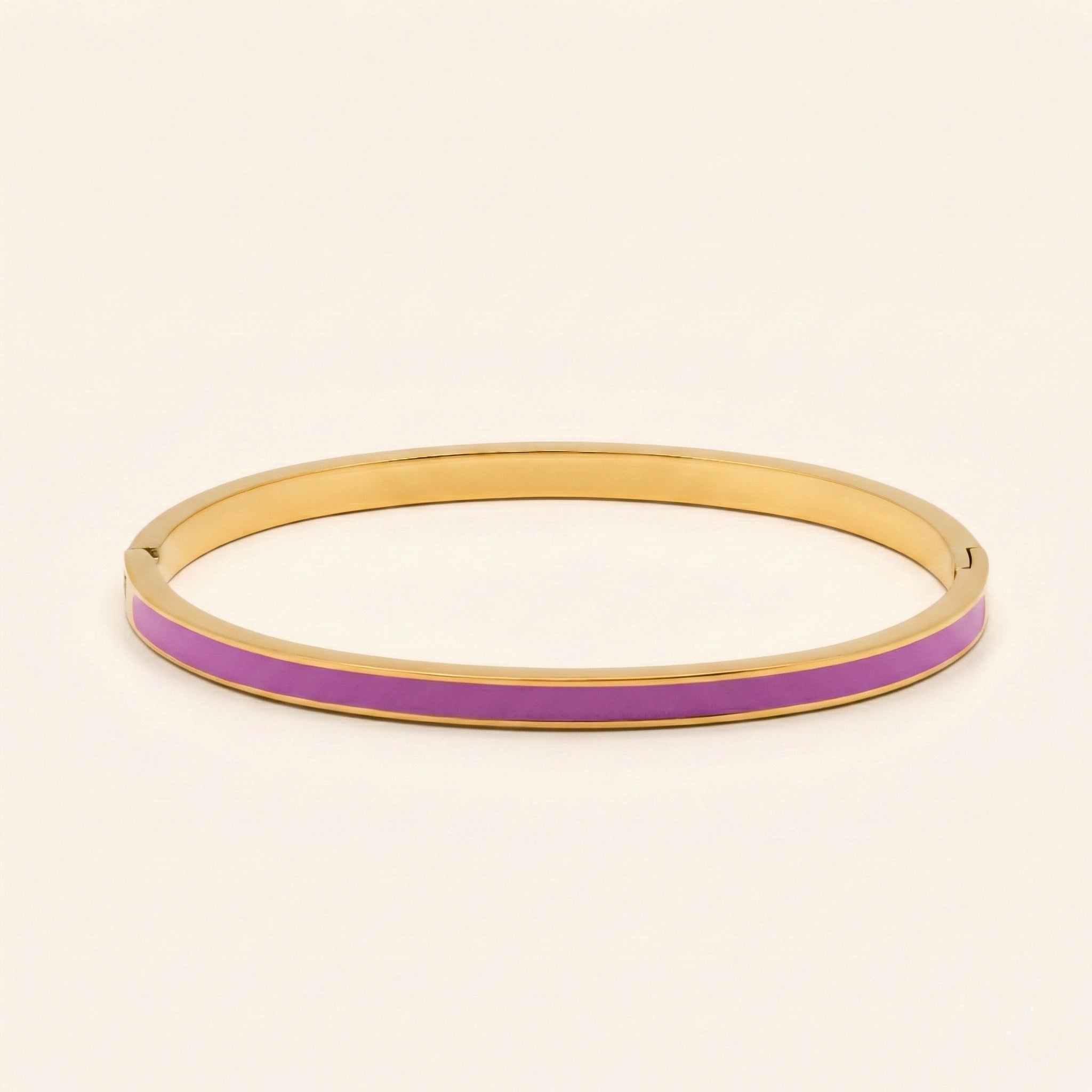 Gold bangle with a purple band on a beige background