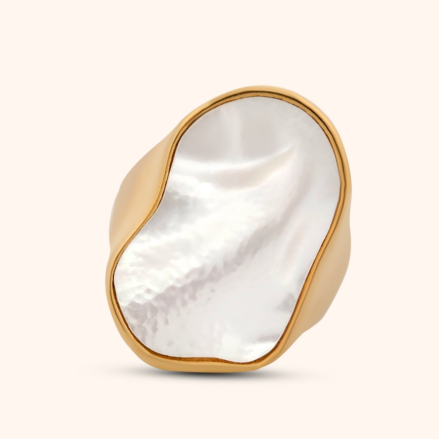 A hand wearing an abstract mother of pearl ring with a sleek gold band, demonstrating its modern and elegant style.