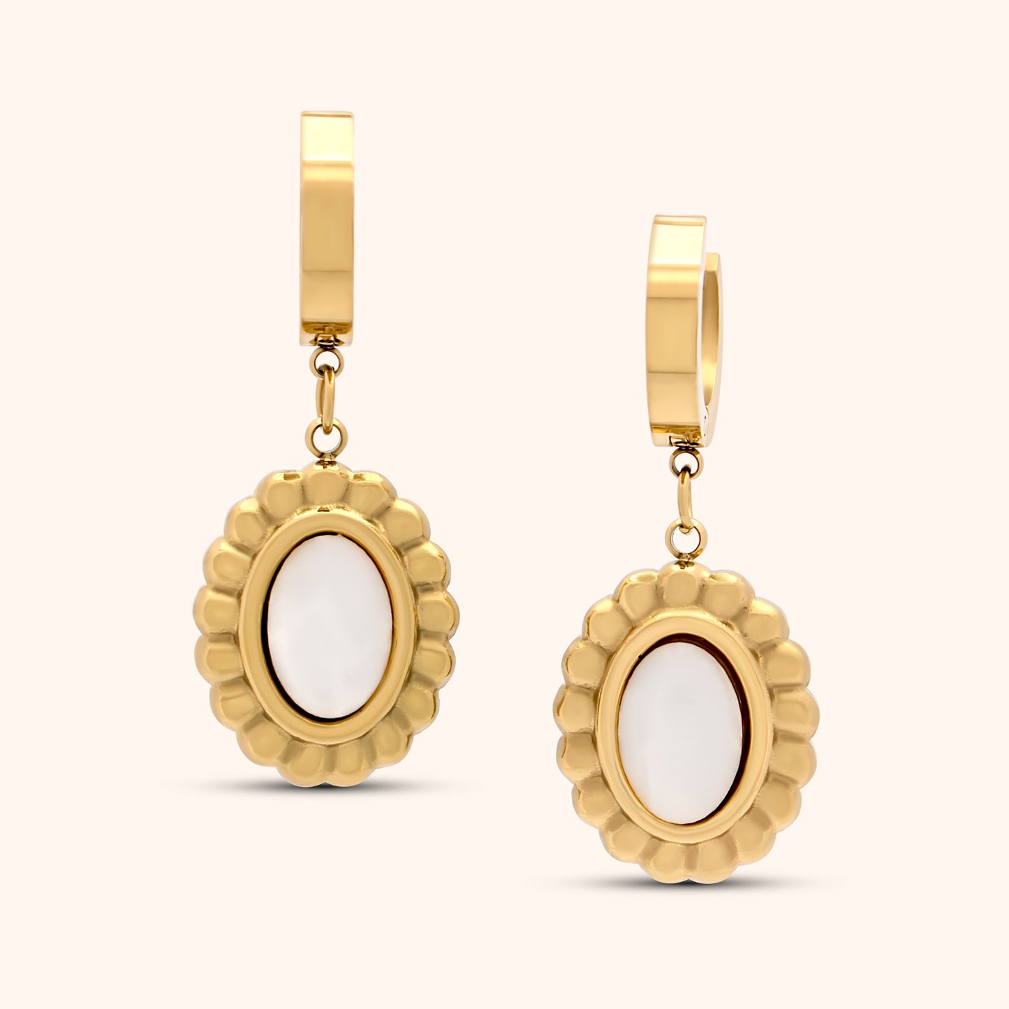 Two PRESSIE Solstice Drop earrings, showcasing the gold hoops and oval white charms with textured gold borders, displayed together