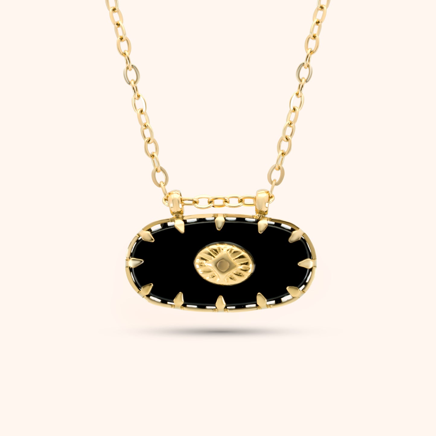 PRESSIE Midnight Sun Pendant; closer view of an 18k gold plated necklace with an elongated black oval pendant featuring gold spike-like prongs and a central round gold charm with a radiating sunburst pattern