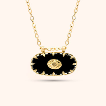PRESSIE Midnight Sun Pendant; closer view of an 18k gold plated necklace with an elongated black oval pendant featuring gold spike-like prongs and a central round gold charm with a radiating sunburst pattern