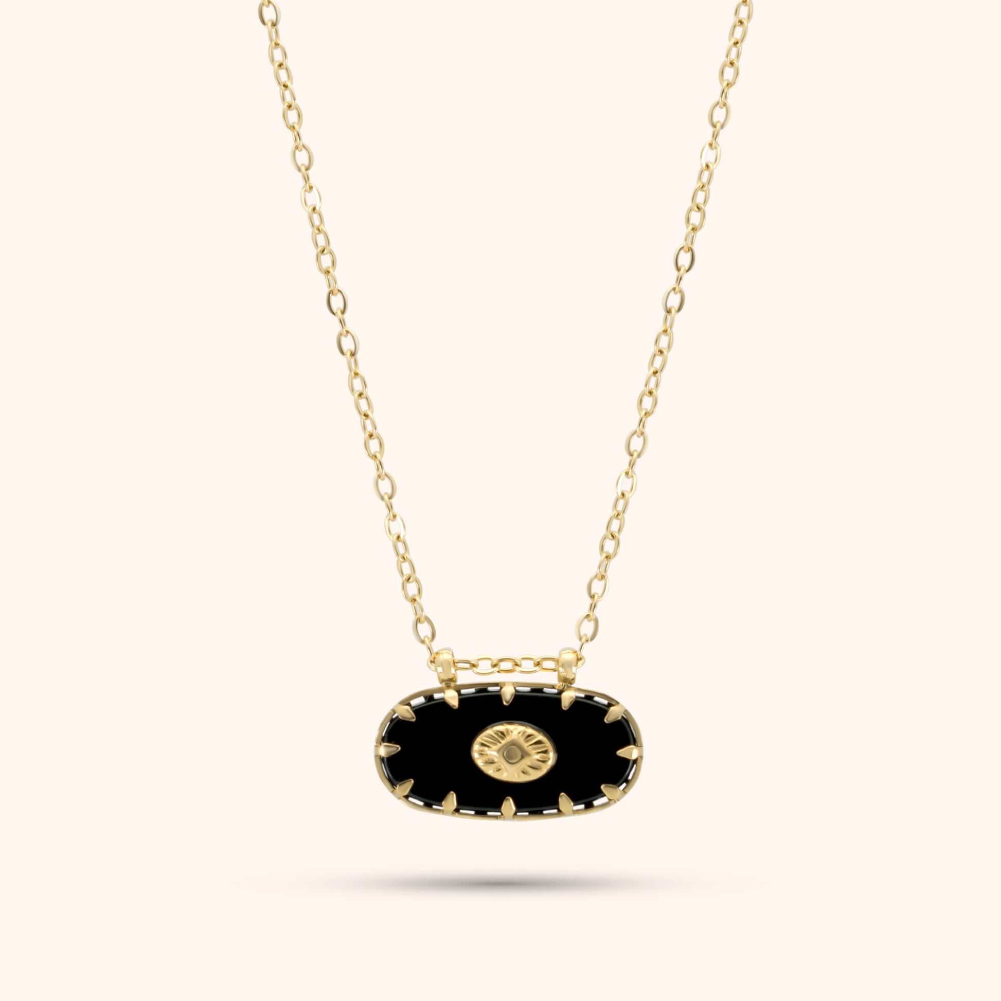 PRESSIE Midnight Sun Pendant; 18k gold plated necklace with an elongated black oval pendant featuring gold spike-like prongs and a central round gold charm with a radiating sunburst pattern