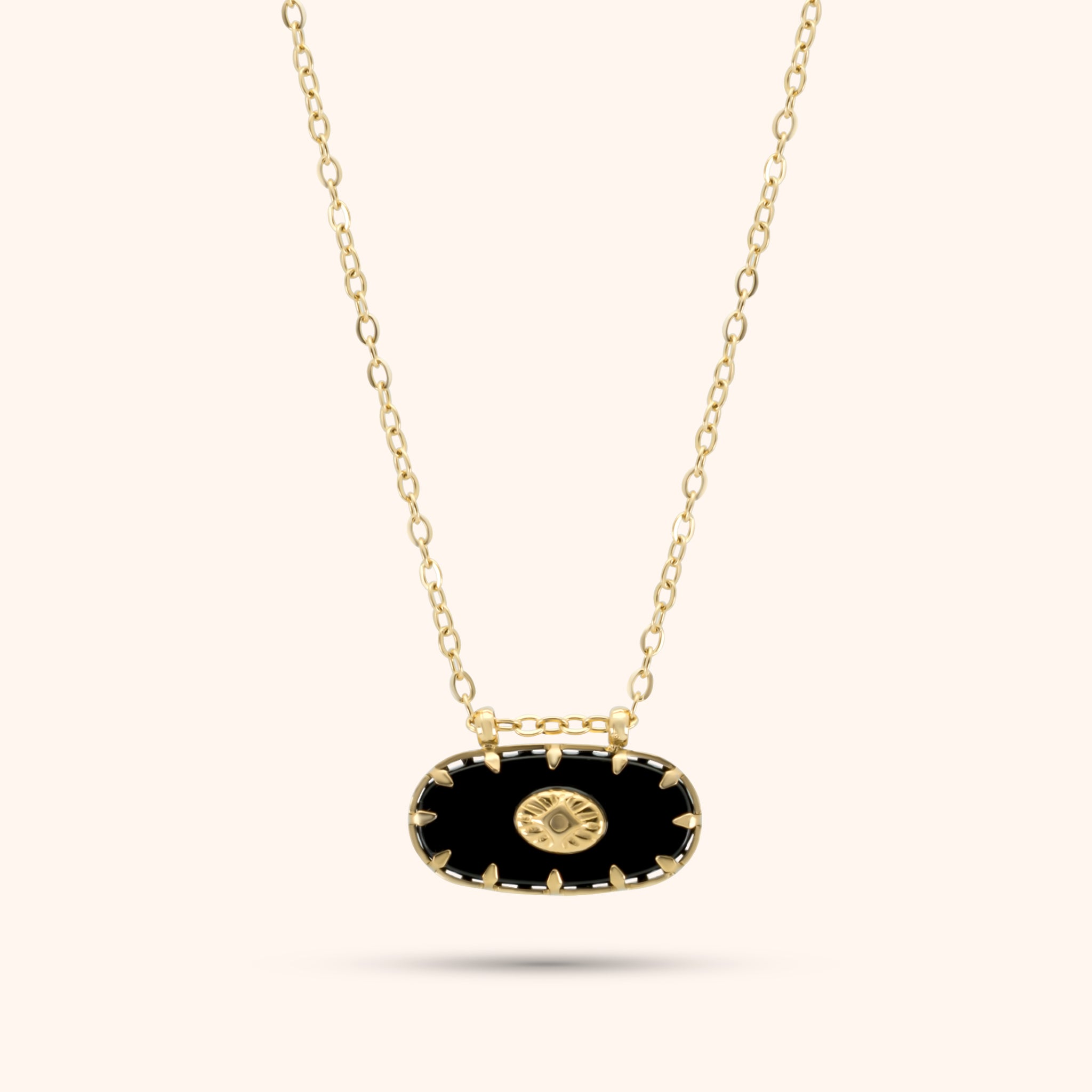 PRESSIE Midnight Sun Pendant; 18k gold plated necklace with an elongated black oval pendant featuring gold spike-like prongs and a central round gold charm with a radiating sunburst pattern