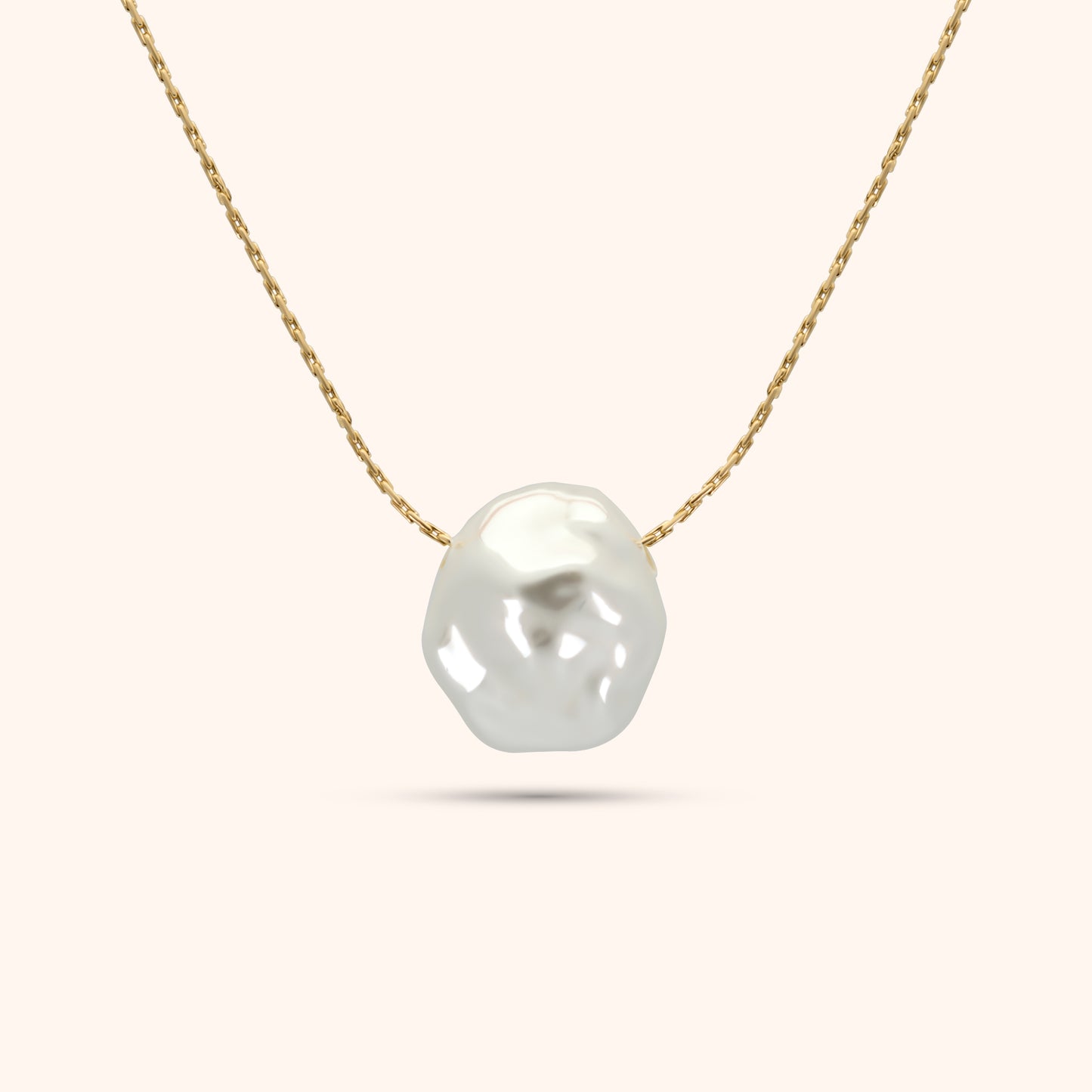 Close-up of the single baroque pearl on the PRESSIE Luster Pearl Necklace; showing its organic shape and luster on an 18k gold plated chain.