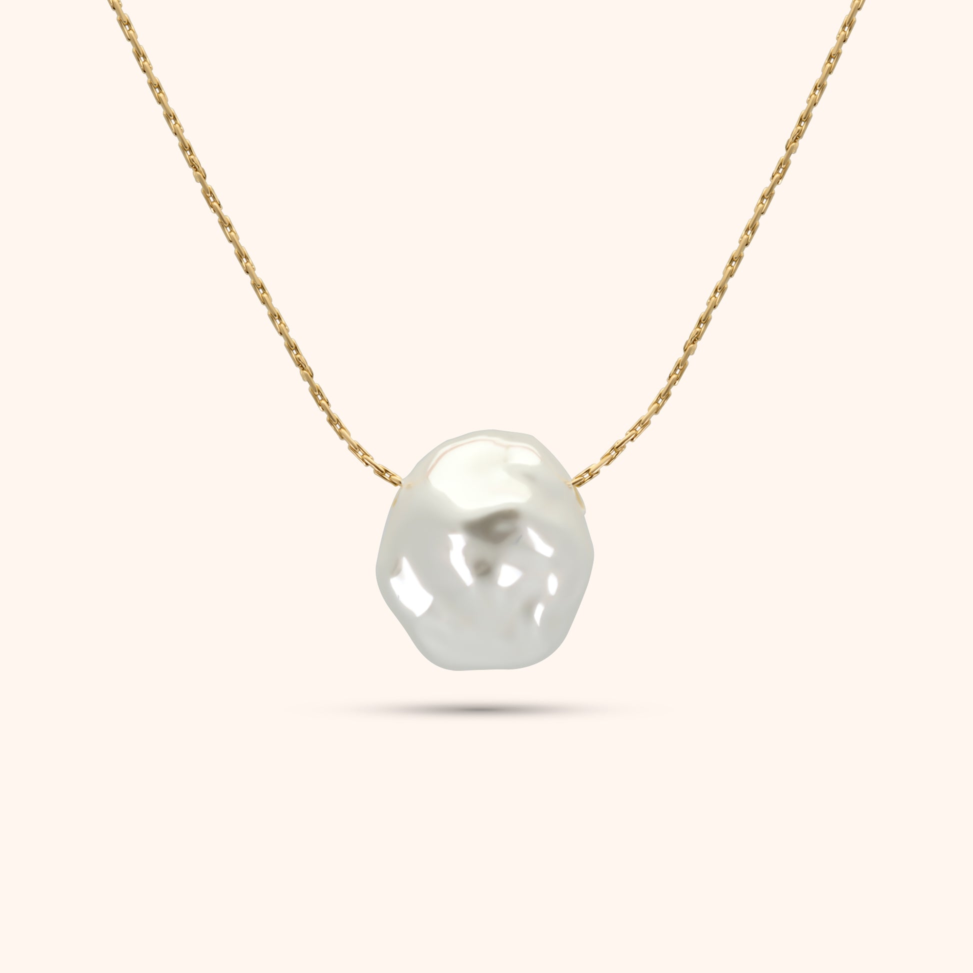 Close-up of the single baroque pearl on the PRESSIE Luster Pearl Necklace; showing its organic shape and luster on an 18k gold plated chain.