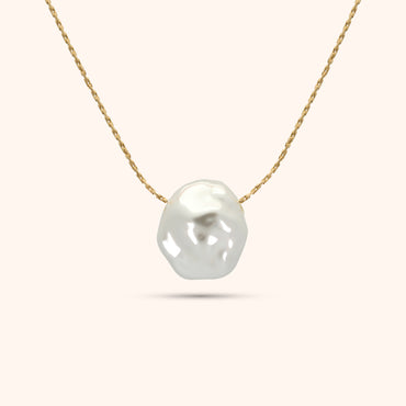 Close-up of the single baroque pearl on the PRESSIE Luster Pearl Necklace; showing its organic shape and luster on an 18k gold plated chain.
