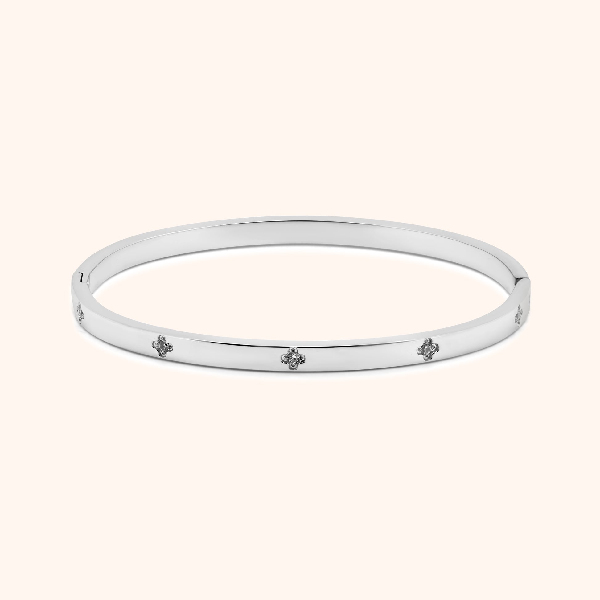 Silver clover bangle bracelet with crystal accents, flat lay