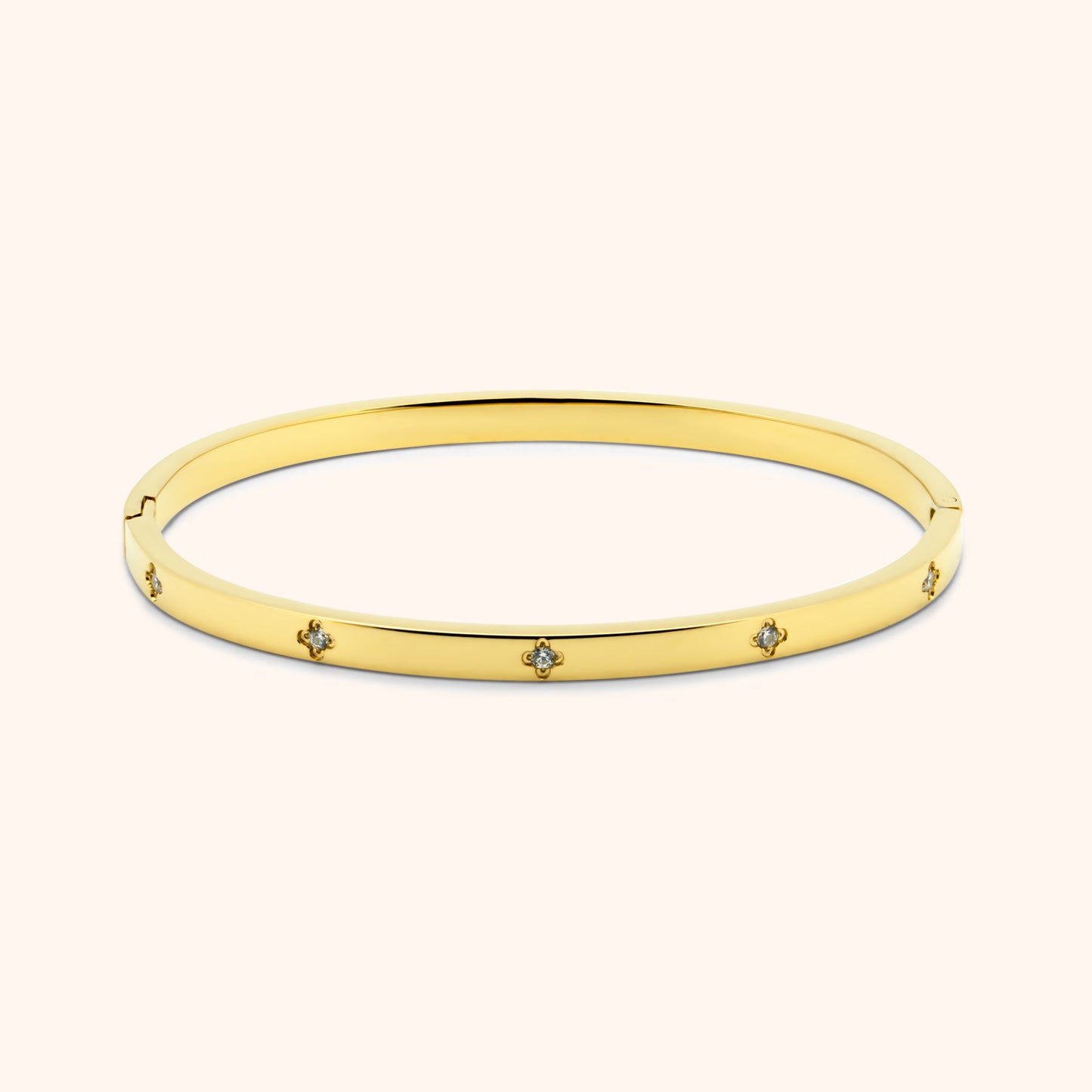 Gold clover bangle bracelet with embedded crystal accents, flat lay