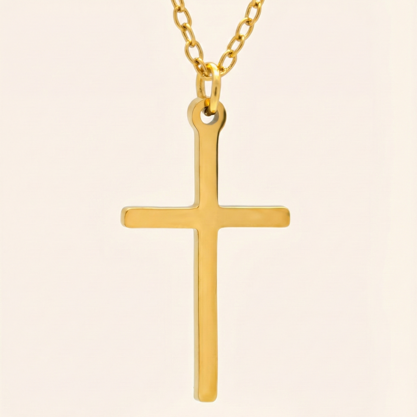 Gold cross pendant on a chain against a beige background