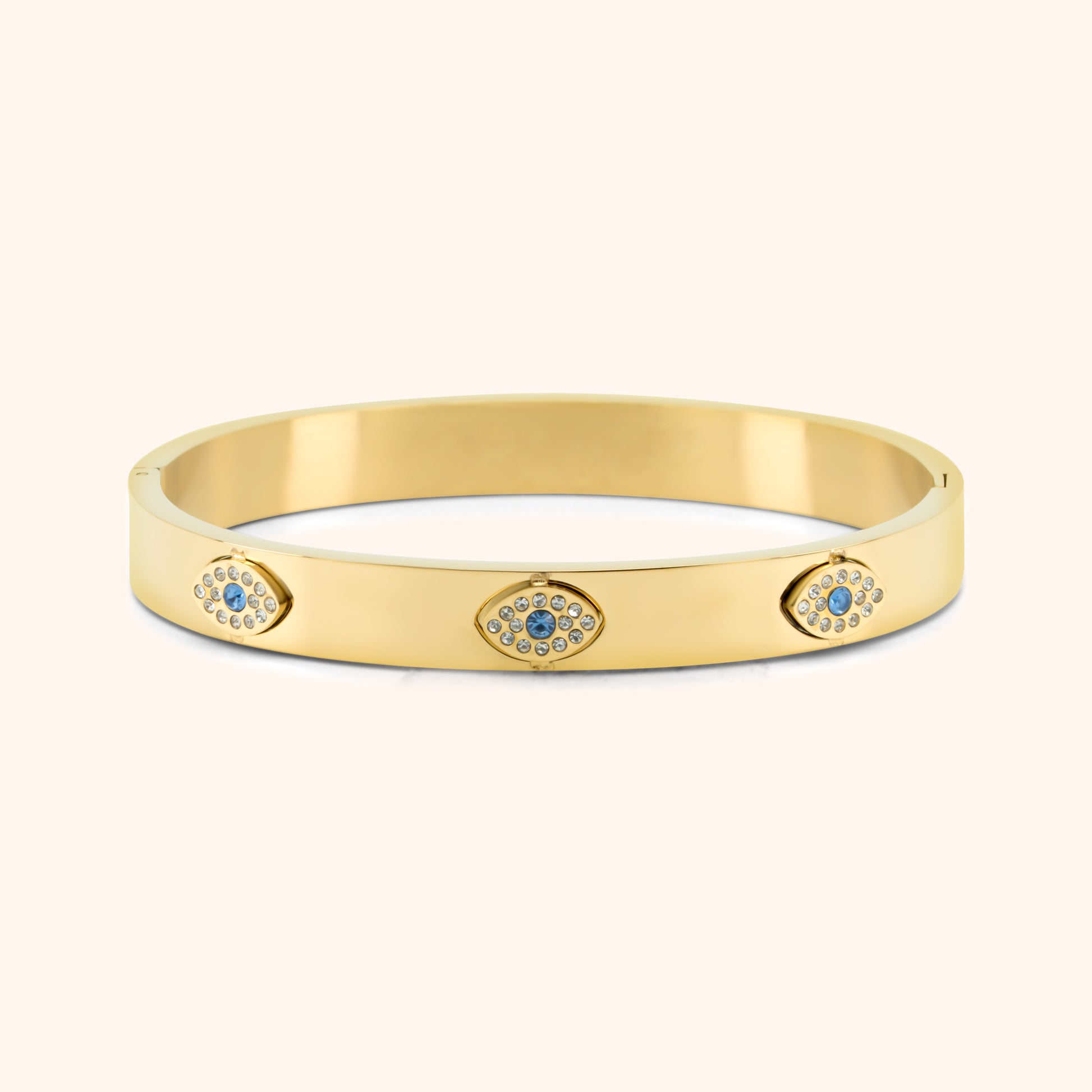 Gold bangle bracelet with three sparkling evil eye charms in blue and clear stones
