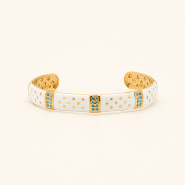 Gold and white bracelet with blue stones on a beige background