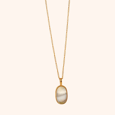 Close-up of The Cozumel Necklace's oval pearl pendant, showcasing its lustrous surface and elegant setting on a delicate gold chain.
