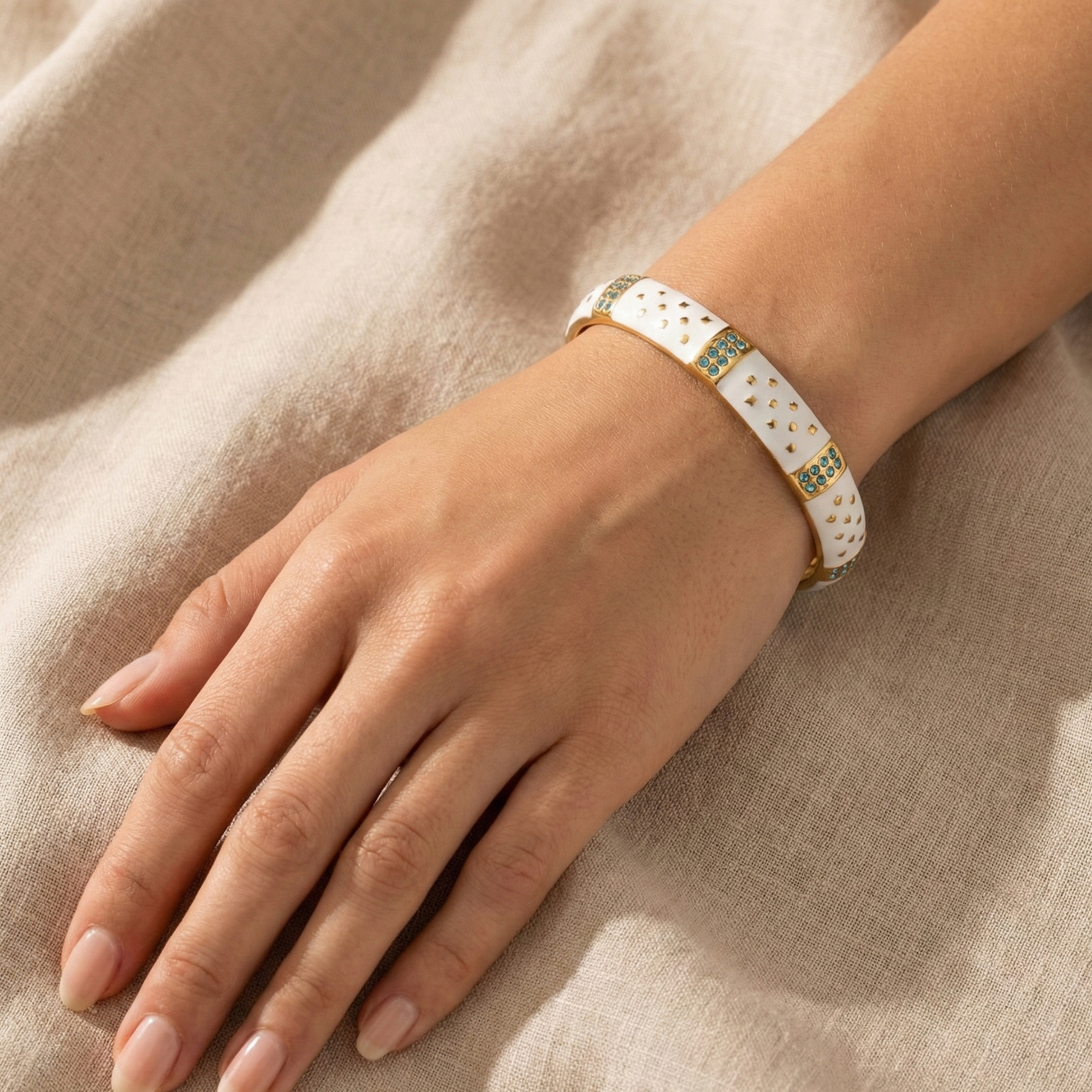 Hand wearing a bracelet on a beige fabric background