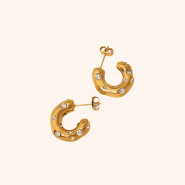 Pair of crystal-embellished chunky gold hoop earrings, highlighting their luxurious texture and glamorous style.
