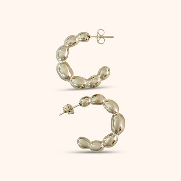 Detailed view of gold balloon hoop earrings showcasing their bold, contemporary design and polished finish