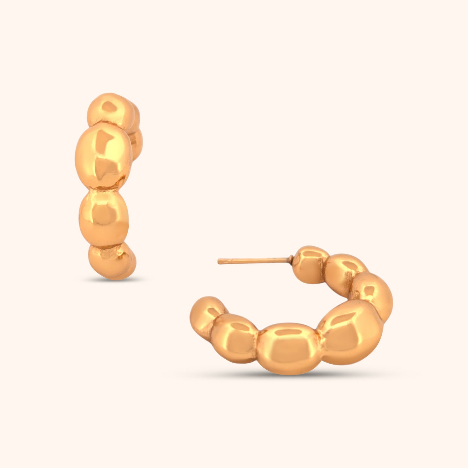 Close-up of gold balloon hoop earrings featuring smooth, rounded beads in a textured, statement design