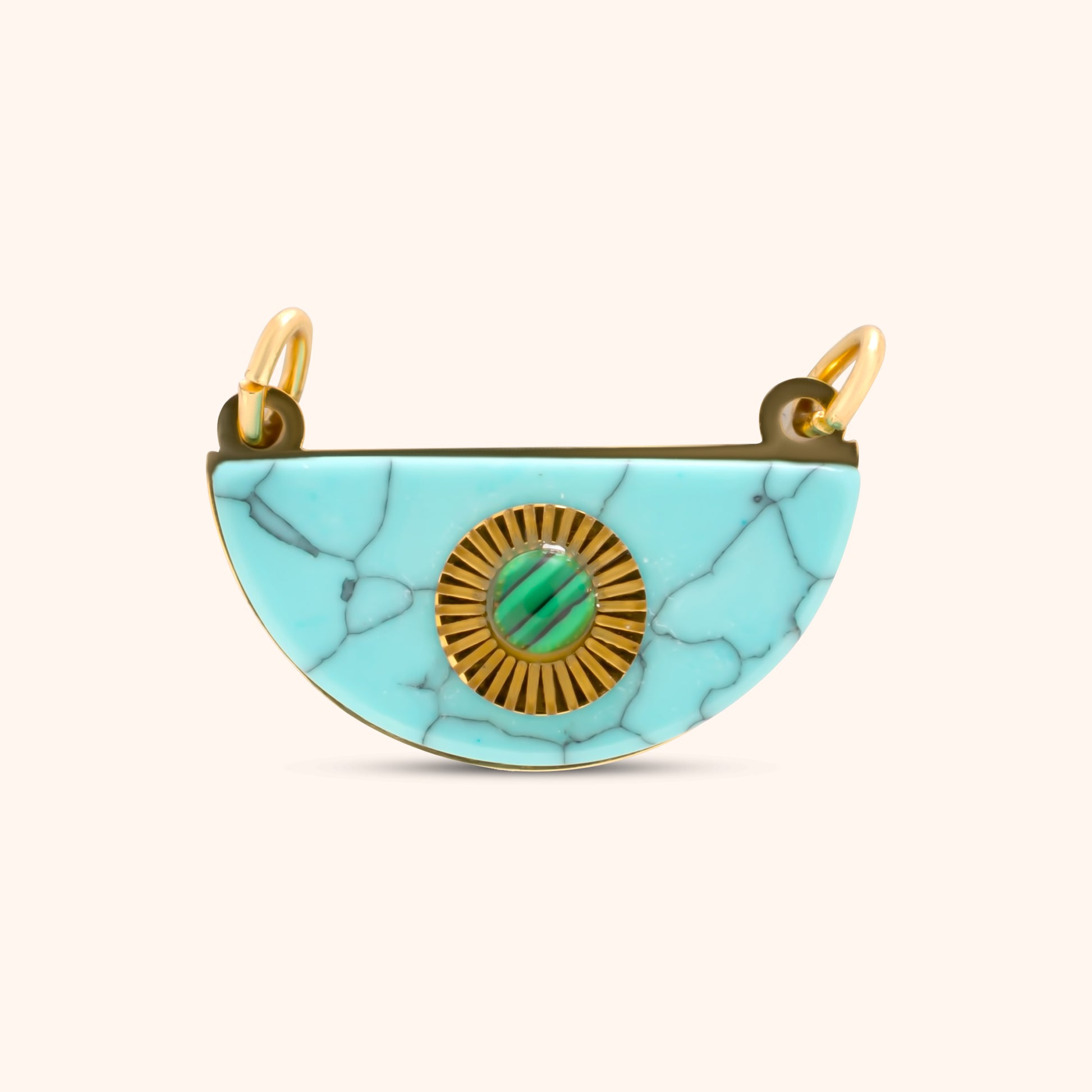 PRESSIE Horizon Charm; an 18k gold plated semi-circular charm made of light blue marbled stone, featuring a central gold sunburst medallion with a small green cabochon stone inset, and two top bails.