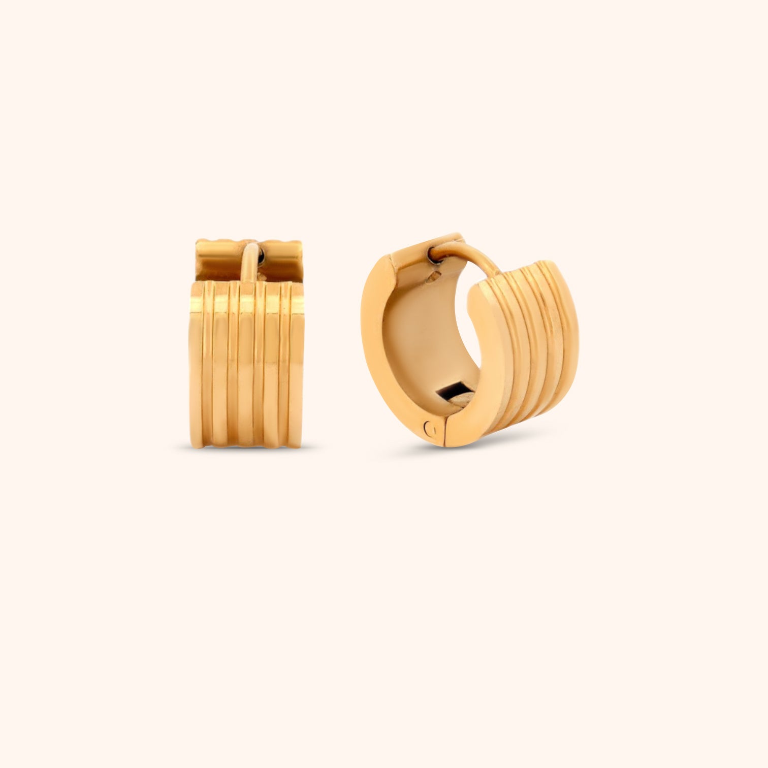 Close-up of gold ribbed huggie earring, showcasing its unique textured design and polished finish.
