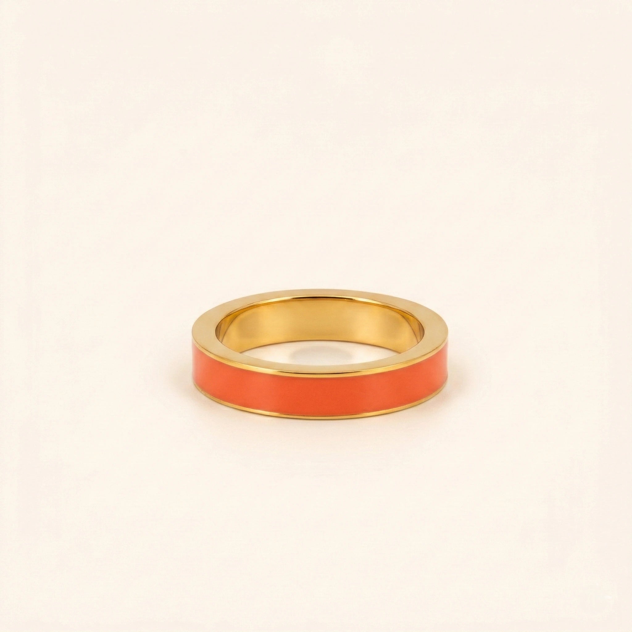 Gold ring with a red band on a beige background