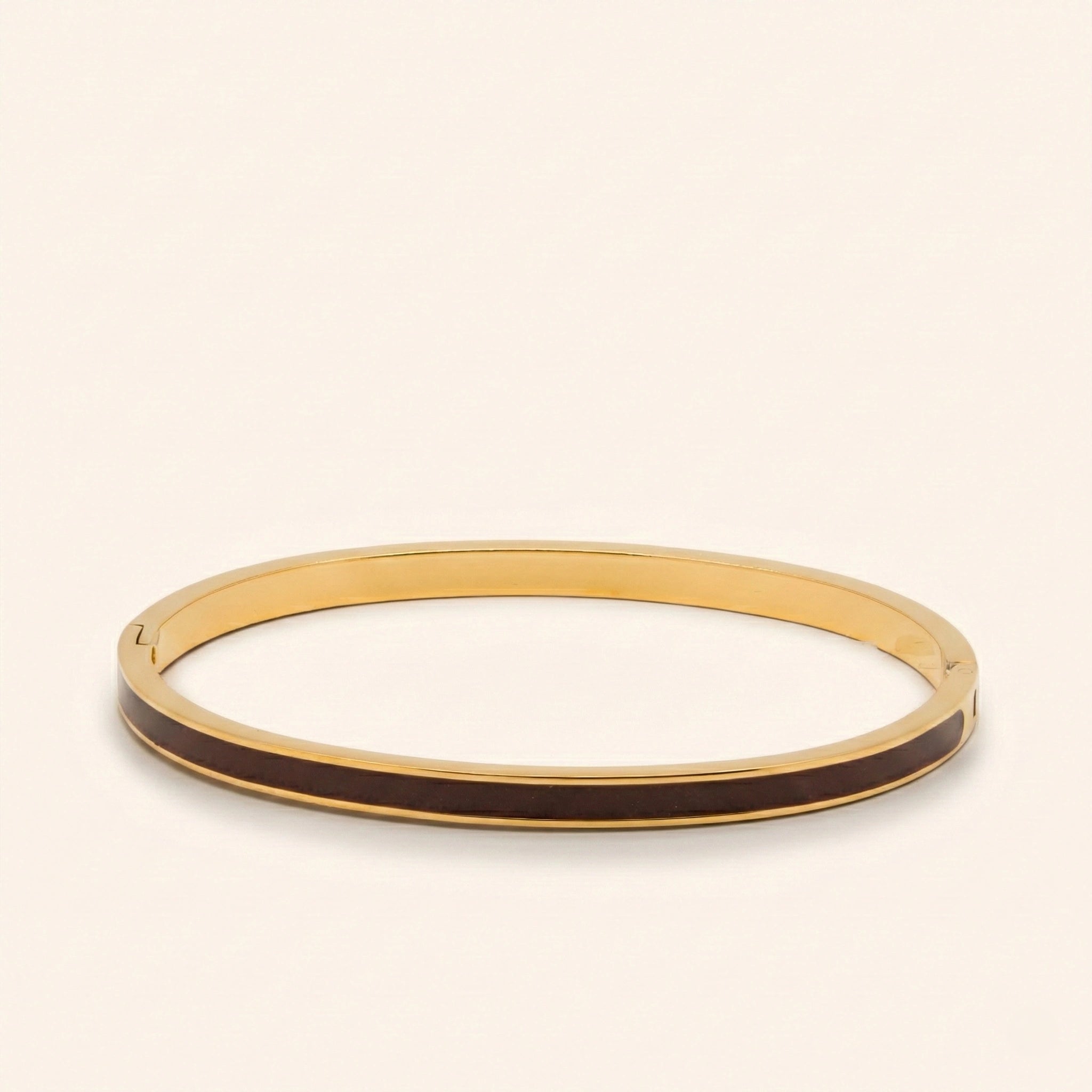 Gold bangle with black interior on a beige background