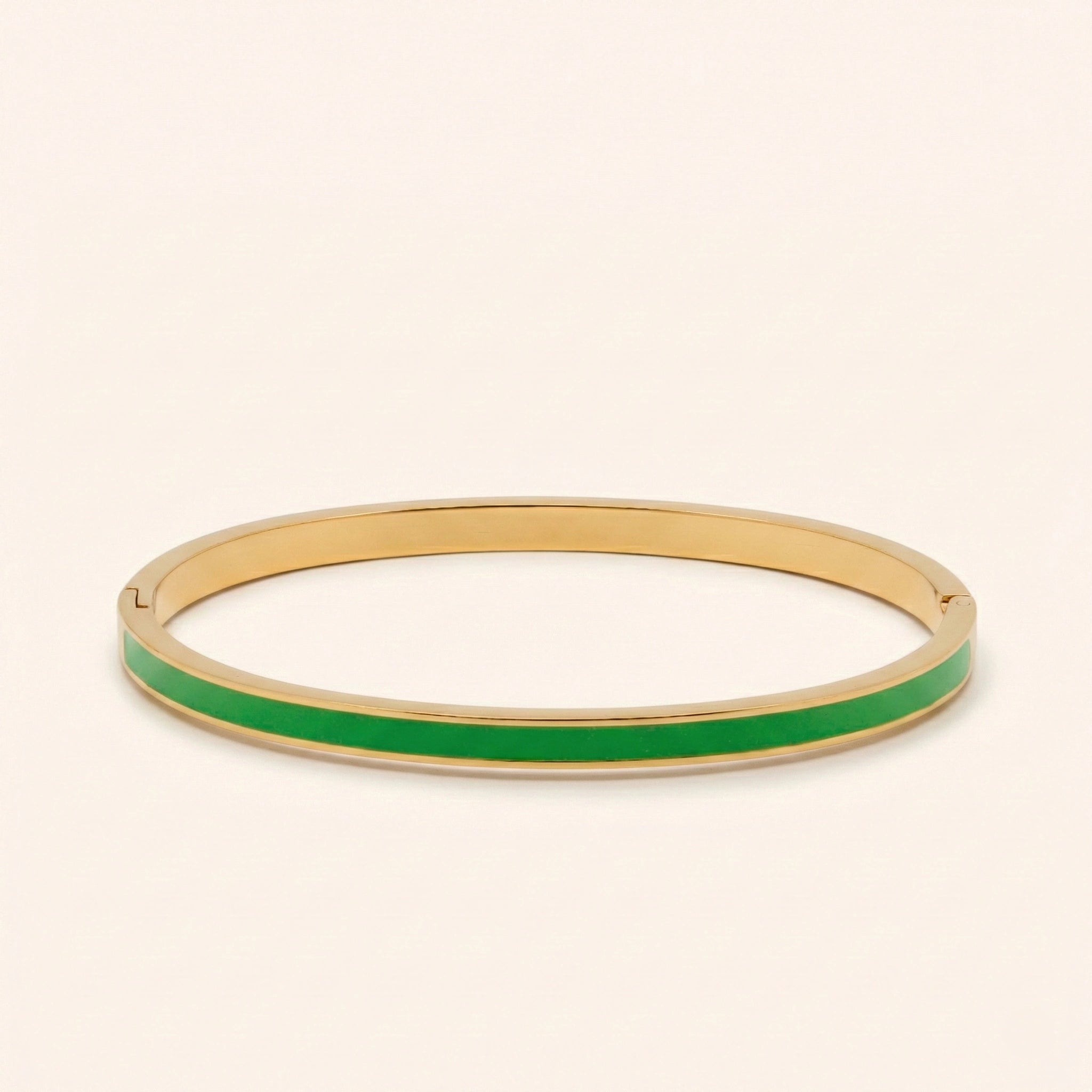 Gold bangle with green interior on a beige background
