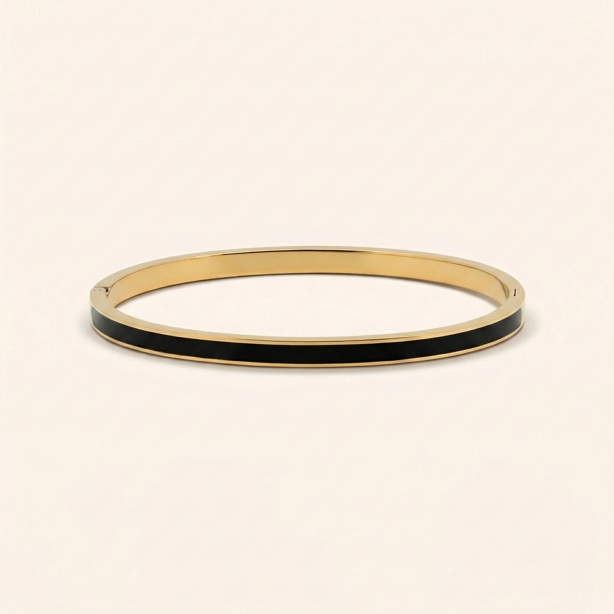 Gold bangle with black interior on a beige background
