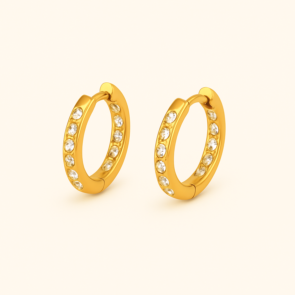 Gold huggie earrings with inset clear crystals along the front, made of 18k gold plated stainless steel with hinged closure