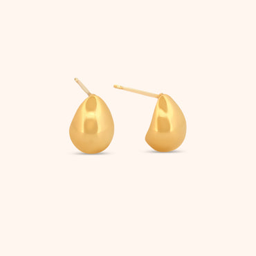 Close-up of gold teardrop earrings, showcasing their smooth, polished surface and modern, sculptural design.
