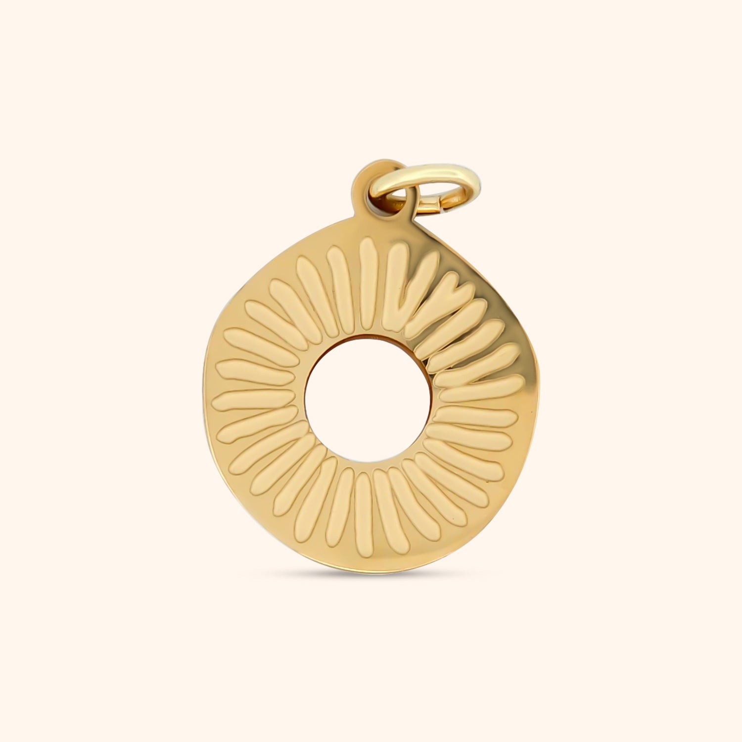 Close-up of the Desert Sun Charm, a circular gold charm featuring a sun design with a small stone at its center.