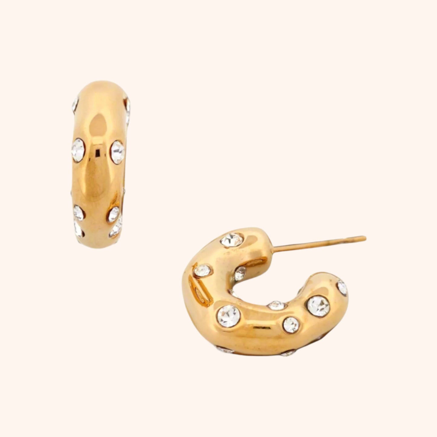 Close-up of a chunky gold hoop earring, showcasing its sparkling crystal embellishments and bold design.
