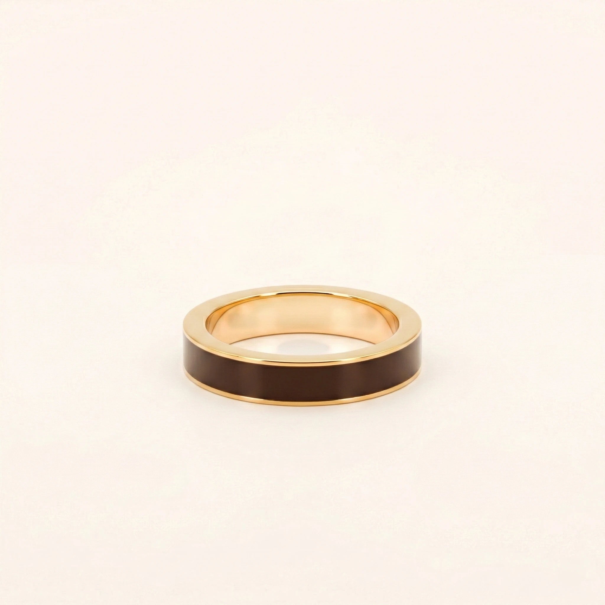Gold ring with a dark brown band on a light beige background