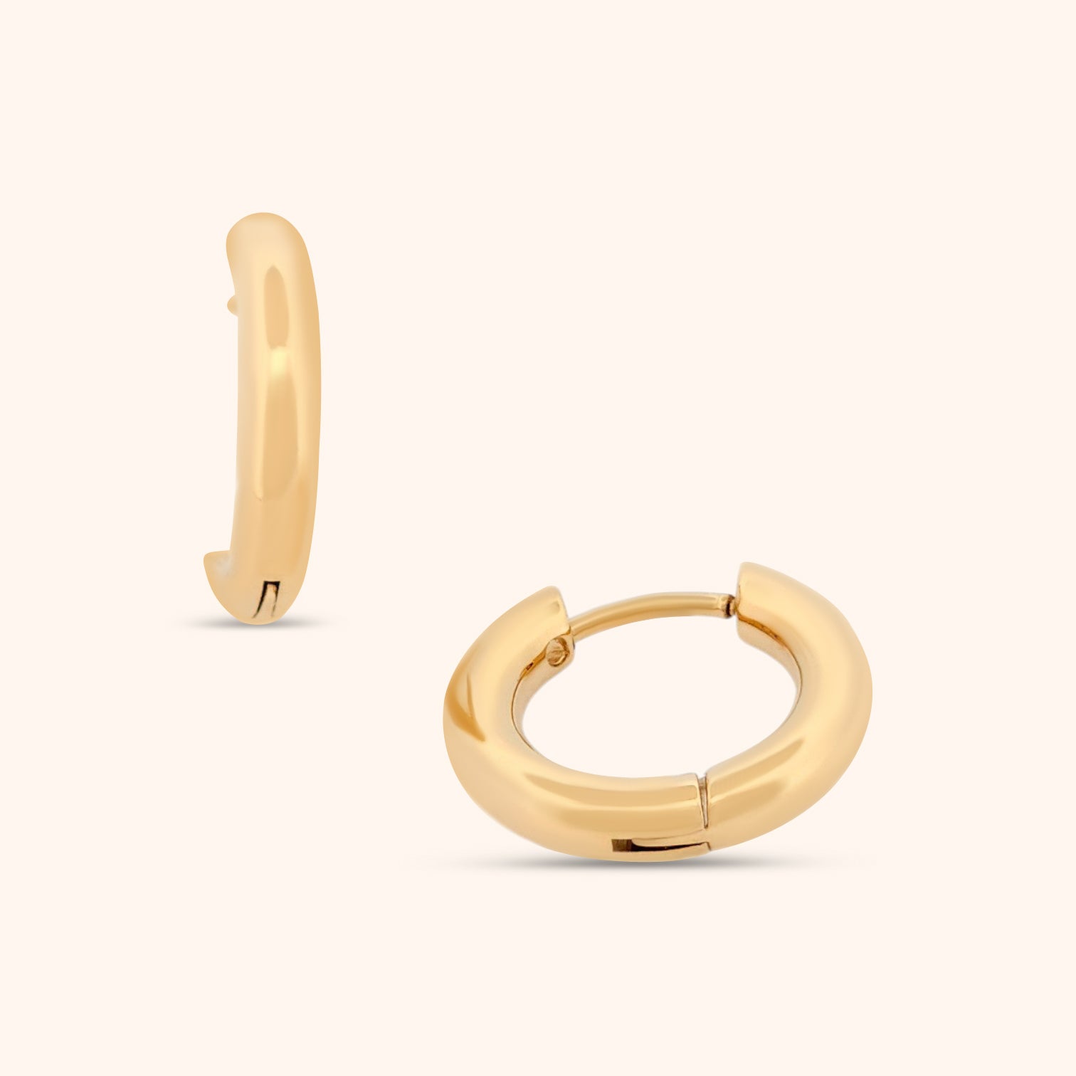 Close-up of small gold huggie earring, showcasing its minimalist design and polished finish.
