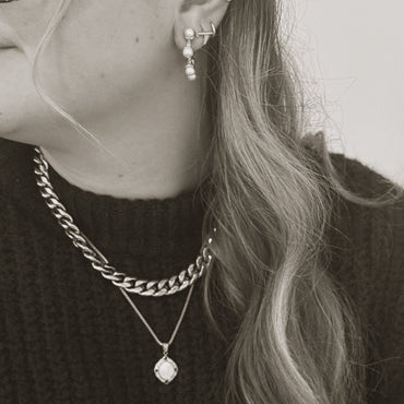 The Voyage Pendant Necklace, a gold necklace with a geometric pendant, worn on a person to demonstrate its size and style